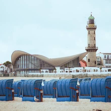 Warnemünder Leuchtturm und Teepott hinter blauen Strandkörben