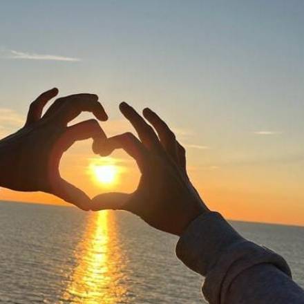 Zwei Hände formen ein Herz vor der Ostsee