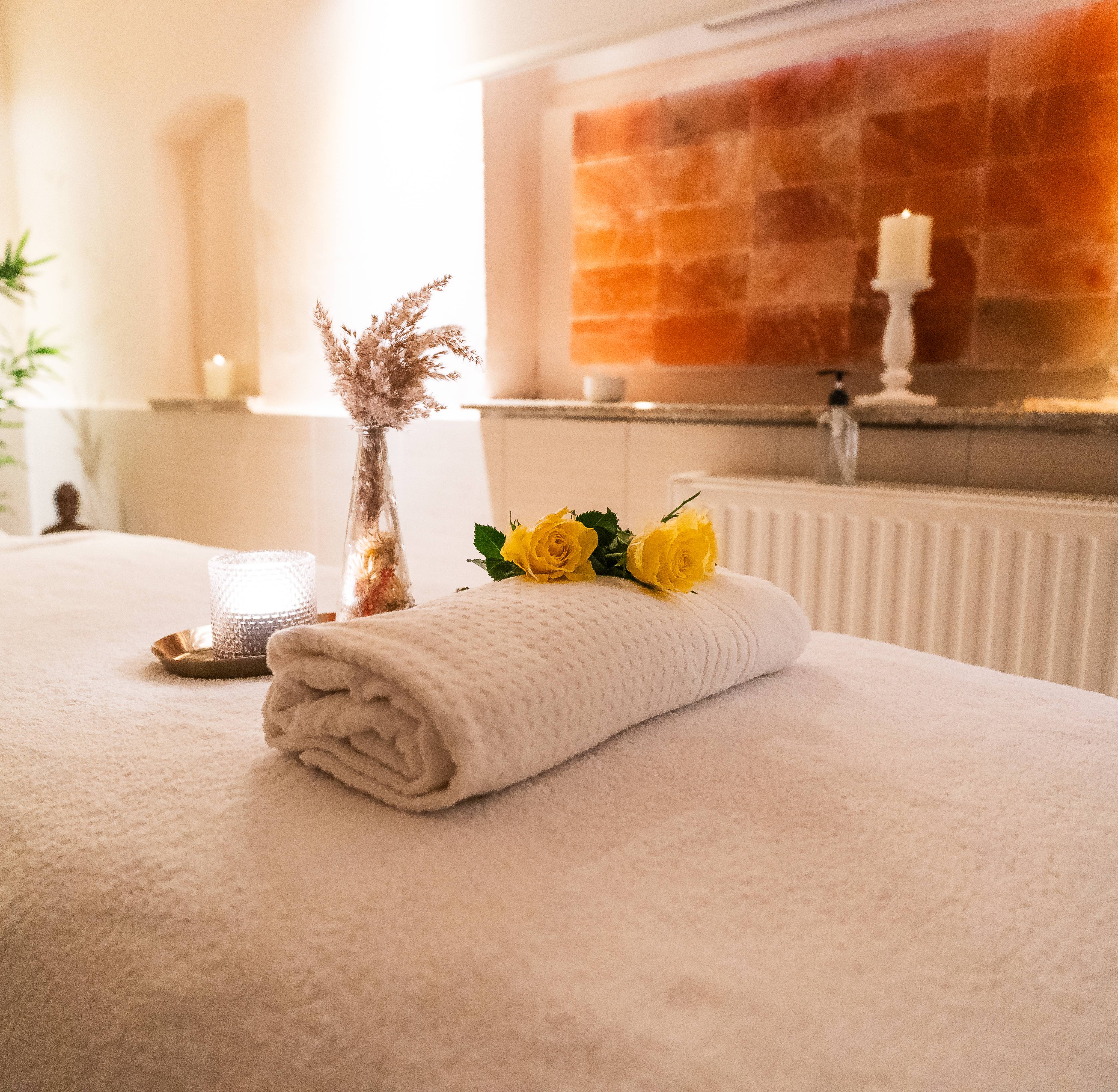 Massageliege mit Handtuch und Dekoration vor einer Salzwand